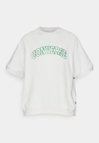 Biała bluza z długim rękawem z haftem "CONVERSE" w kolorze zielonym. Krótkie rękawy raglanowe i okrągły dekolt. Miękka tkanina o luźnym kroju.