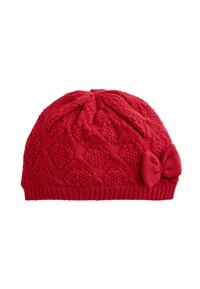 Bonnet tricoté rouge avec un motif texturé en losanges, agrémenté d'un nœud sur le côté et d'une bande côtelée ajustée à la base.