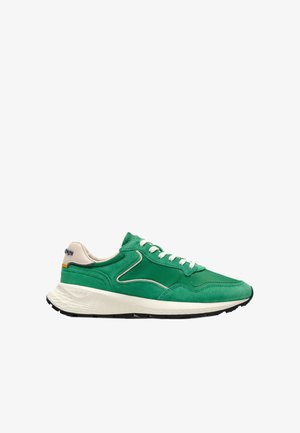 Sneaker verde e beige con lacci bianchi e suola bianca texturizzata, mostrata di lato su uno sfondo bianco.