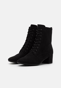 Stivali alla caviglia in suede nero con un design alto a lacci, punta appuntita e tacco a blocco. Presentano occhielli e una trama sottile sulla superficie.