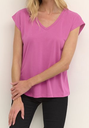 Fuksjowy krótki rękaw, dekolt w serek, wykonany z miękkiej tkaniny, o luźnym kroju i prostym wzorze, zestawiony z czarnymi spodniami.