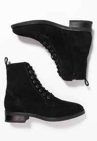 Stivali alla caviglia in suede nero con punta rotonda, lacci frontali e cerniera laterale, completati da un tacco basso impilato e suola texturizzata.