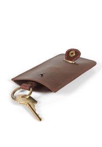 Porte-clés en cuir marron avec un design incurvé, doté d'un anneau en laiton pour les clés et d'une fermeture à pression. La surface a une texture lisse.