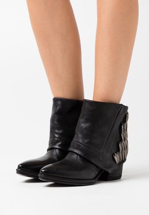 Zwarte leren enkellaarsjes met een omgeslagen ontwerp, versierd met metalen accenten aan de zijkanten en een lage, vierkante hak.