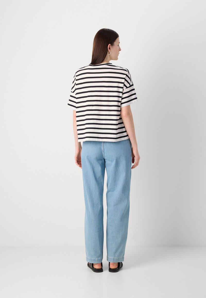 Gestreiftes T-Shirt in Schwarz und Weiß, kurze Ärmel, lässiger Schnitt, kombiniert mit hellblauen, hochgeschnittenen Jeanshosen. Einfaches und lässiges Design.