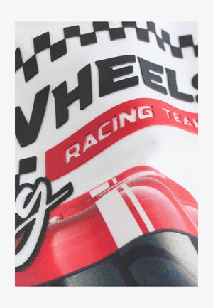 Bela tkanina z črnimi in rdečimi grafikami s tematikos dirkanja, vključno s tekstom in šahovskim vzorcem. Tekstura se zdi gladka in natisnjena.