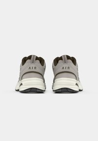 Pantofi sport gri cu un superior texturat, talpă intermediară albă și talpă exterioară neagră. Include branding "AIR" pe călcâi.