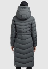Manteau rembourré gris long avec un motif en chevrons, une grande capuche et une fermeture éclair. Présente une texture matelassée et des manches ajustées.