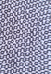 Motivo tessile con piccoli cerchi blu navy all'interno di contorni esagonali su uno sfondo blu chiaro. Texture del tessuto liscia.