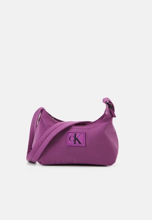 Fialová taška přes rameno Calvin Klein s nastavitelným popruhem a černou nášivkou s logem „cK“ vpředu na bílém pozadí.