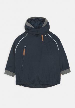 Marineblauwe waterdichte jas met een capuchon, grijze geribbelde boorden en zijzakken met rits. Voorzien van witte bies en een bruin leren accent.