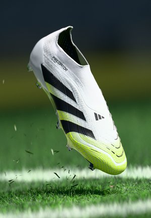White soccer cleat with black and neon green accents. Textured upper material, streamlined design, and visible studs for traction.