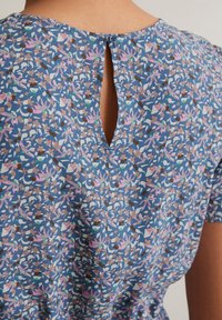 Blumenkleid aus blauer Stoff mit rosa, weißen und braunen Mustern, runder Ausschnitt mit einem Knopfverschluss hinten und kleinem Schlitzdetails.