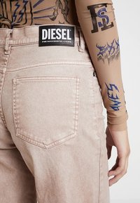 Vaaleanpunaiset denim-farkut korkealla vyötäröllä, joissa on erottuva musta Diesel-logo-ompelu takana, sisältäen yhden takataskun.