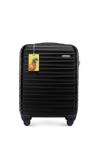 Black hard-shell suitcase with horizontal ridges, featuring a plastic handle, four wheels, and a colorful pineapple luggage tag.