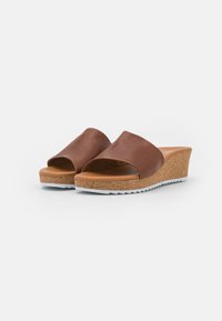 Sandales compensées en cuir marron avec un design à bout ouvert, semelle en liège et semelle en caoutchouc blanc. Texture lisse et élégante avec une forme arrondie.
