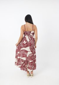 Robe maxi avec un corsage ajusté, des bretelles spaghetti réglables, et un imprimé feuillage en bordeaux et crème, dotée d'une jupe fluide.
