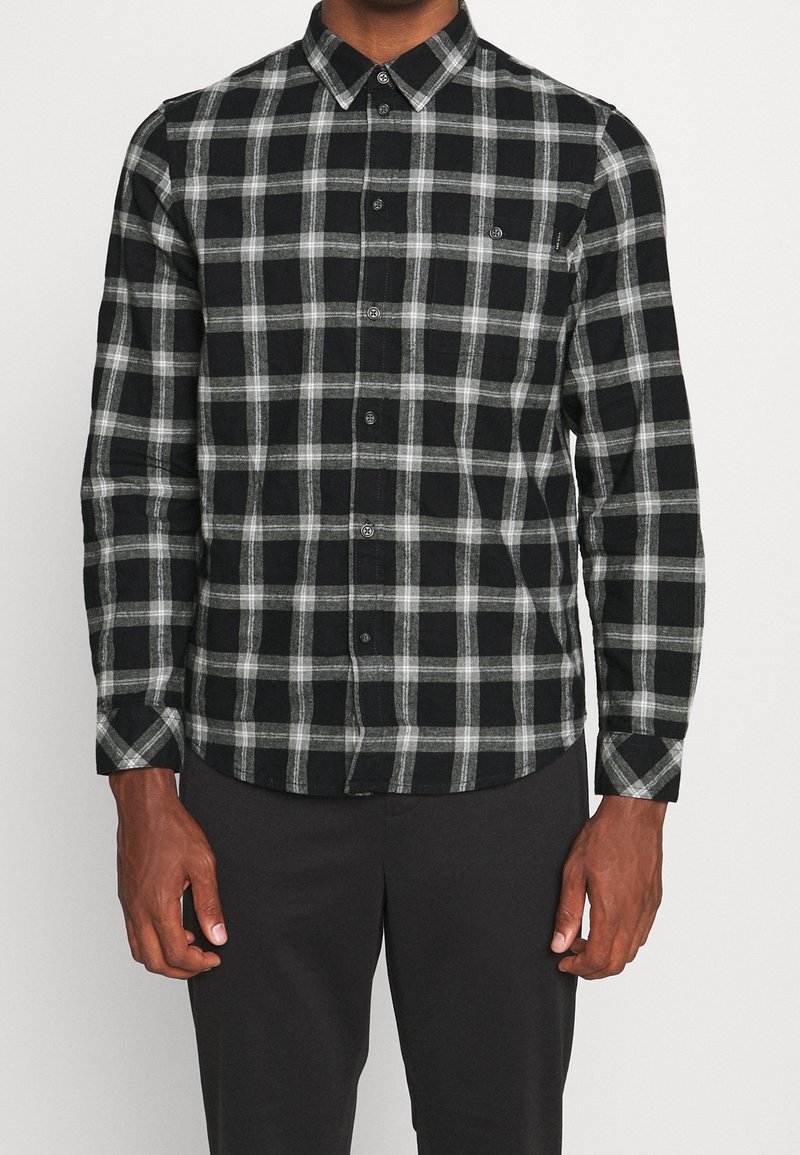 Camicia a quadri nera e grigia con colletto aperto e maniche lunghe, dotata di taschino sul petto e tessuto morbido.