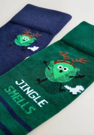 Sokipaar; üks tumesinine, millel on tegelane ja sarved, teine roheline, millel on tegelane, tekst "JINGLE SMELLS" ja valged detailid. Pehme kudumise tekstuur.