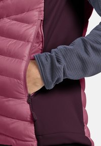 Giacca foderata in pile con un corpo trapuntato rosa e pannelli laterali marrone scuro. Presenta una tasca con zip e uno strato sottostante a maniche lunghe blu.