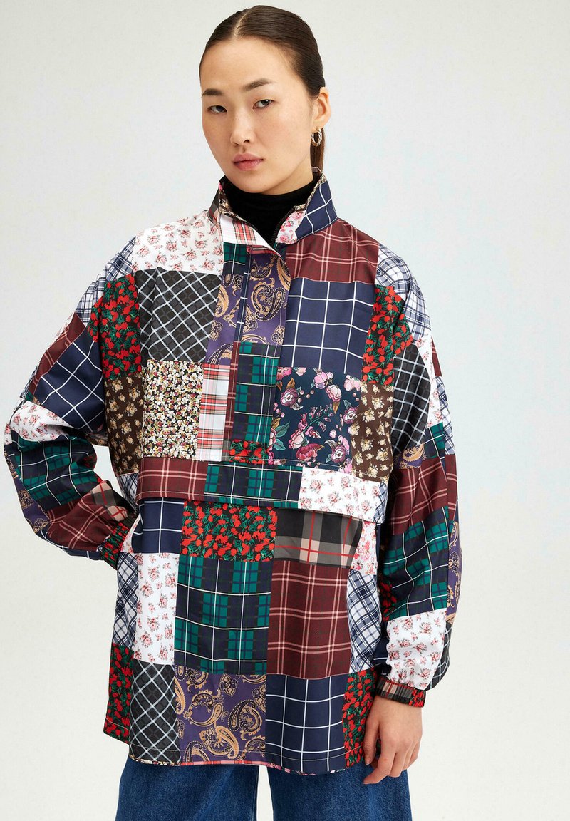 Patchwork shirt met verschillende patronen in bloemen-, ruit- en paisleyontwerpen. Kleuren zijn onder andere bordeaux, marineblauw, groen en wit. Lange mouwen.