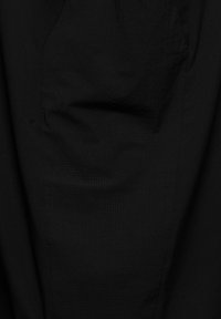 Gros plan sur un tissu noir avec un motif subtil de carrés texturés et le contour d'une poche cousue.