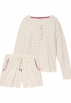 Loungewear-Set in Creme, bestehend aus einem langärmeligen Oberteil und Shorts mit kleinen roten Herzmustern sowie kontrastierenden roten Einfassungen an Taschen und Ausschnitt.