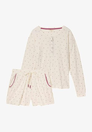 Loungewear-Set in Creme, bestehend aus einem langärmeligen Oberteil und Shorts mit kleinen roten Herzmustern sowie kontrastierenden roten Einfassungen an Taschen und Ausschnitt.