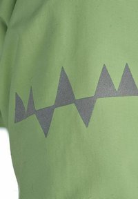 Grön textilväv med en strukturerad yta som har ett grått zigzag-mönster längs nederkanten.