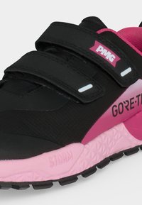 Gros plan d’une basket noire et rose avec deux bandes Velcro, les logos PMG et Gore-Tex, et une semelle rose texturée marquée "STORM."