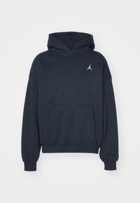 Sweat à capuche bleu marine à manches longues, poche kangourou à l'avant et petit logo blanc Jumpman sur le haut gauche de la poitrine.