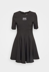 Black short-sleeve dress with fitted bodice and flared skirt. Features a zipper at the back and a label on the chest. Smooth texture.