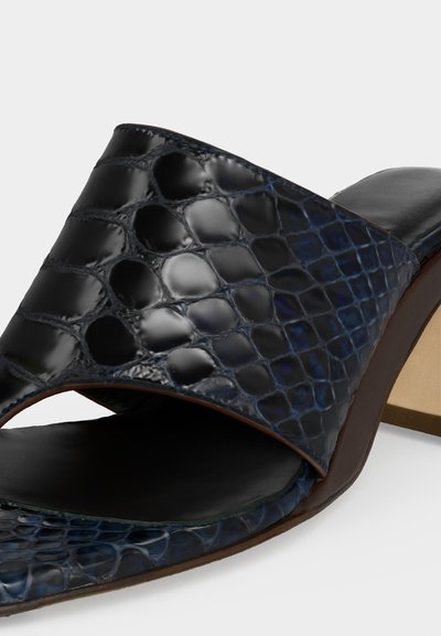 Μαύρο γυναικείο mule με ψηλό τακούνι, γυαλιστερό επάνω μέρος από δέρμα με ανάγλυφο σχέδιο κροκό και ανοιχτό μπροστινό μέρος.