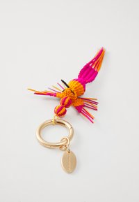 Porte-clés coloré avec un motif d'oiseau tissé en rose et orange, attaché à un anneau de clé circulaire en ton doré avec une petite étiquette ovale.
