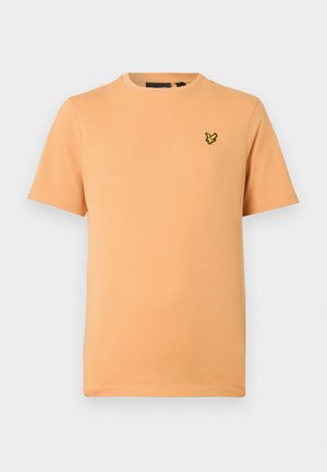 Krótki rękaw t-shirt z miękkiej bawełny w kolorze brzoskwiniowym. Posiada okrągły dekolt oraz małe żółte haftowane logo na lewej piersi.