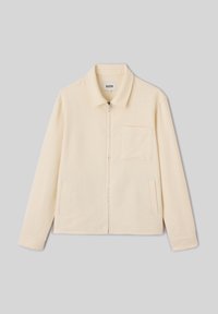 Veste beige à manches longues zippée avec col, poche poitrine gauche, et deux poches latérales, posée à plat sur fond gris.