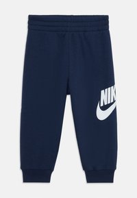 Tumedan sinised Nike trennipüksid elastse vöökoha, ribakäppide ja suure valge logoga vasakul küljel. Pehme ja veniv kangas mugavuse jaoks.