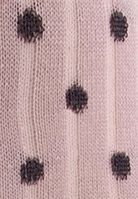 Hellrosa gestrickter Stoff mit erhabenen schwarzen Punkten überall, der Textur und Muster in das Design einbringt.