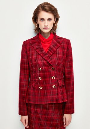 Blazer de cuadros rojos de corte cruzado con acentos en botones dorados, solapas con muesca y bolsillos; usado sobre un suéter de cuello alto rojo.