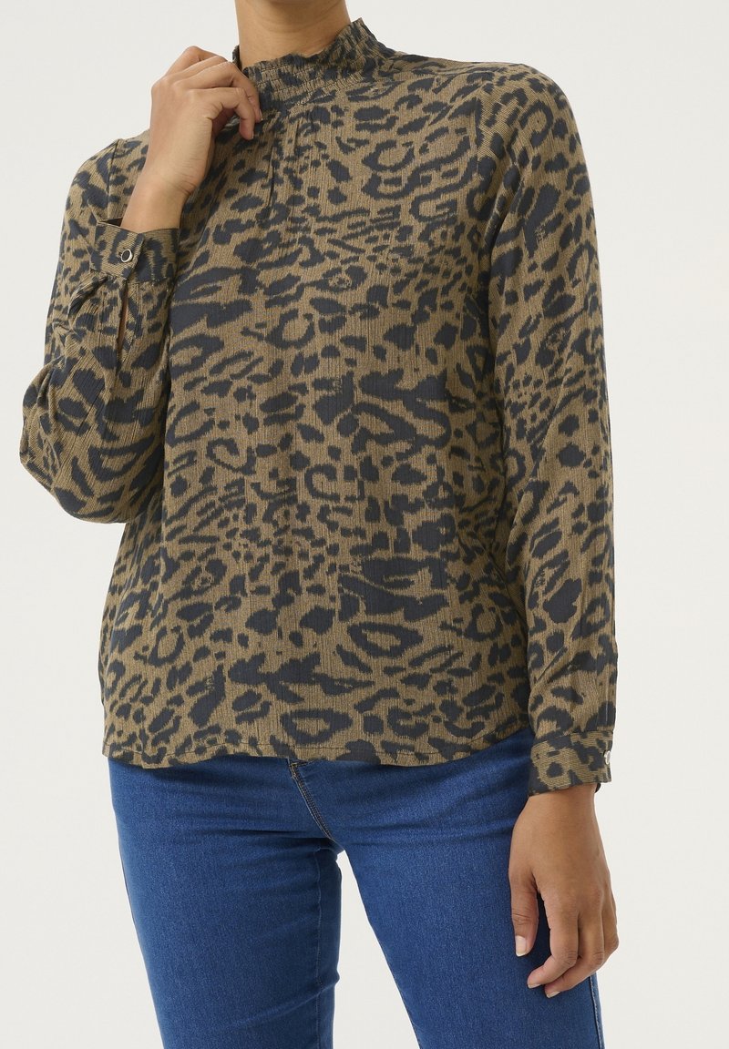 Leopardprint-bluse med høj hals, lange ærmer med knapdetaljer, i varme toner af brun og sort tekstureret stof.