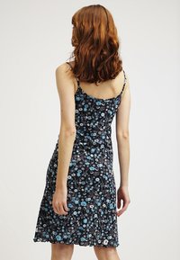 Blumenkleid mit dünnen Trägern; schwarzer Hintergrund mit blauen und weißen Blumen; leichtes Gewebe, ausgestellter Schnitt und gewellter Saum.