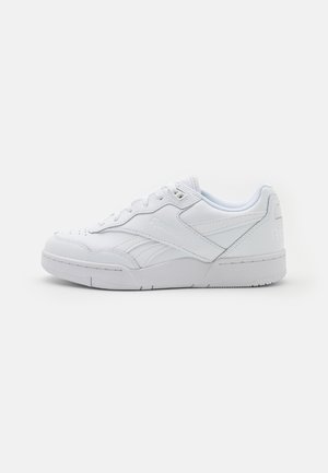 Hvid lavtop sneakers med snørelukning, tekstureret sål og diskret Reebok-mærke på siden og hælen, vist i sideprofil.