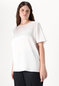 Blusa a maniche corte rosa chiaro con scollo tondo, realizzata in tessuto liscio, con una vestibilità comoda e una leggera lucentezza.