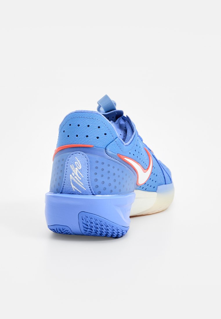 Zapatilla deportiva azul con un upper texturizado, paneles perforados y un swoosh blanco. Presenta una suela blanda y una lengüeta para facilitar el calzado.