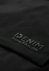 Fekete anyag, textúrált mintával, kiemelkedő "DENIM TOM TAILOR" logóval, amely a felületen jól láthatóan helyezkedik el.