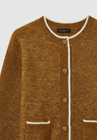 Brauner Strickcardigan mit rundem Halsausschnitt, weißer Besatz, fünf Knöpfen und zwei vorderen Taschen. Strukturierter Stoff, legeres Design.