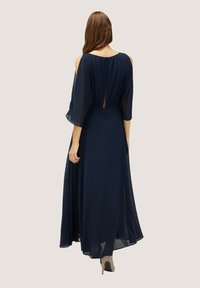 Mörkblå maxiklänning i chiffong med flödande capesärmar och en slits bak, med bakstängning och mjukt, texturerat tyg.