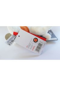 White plush toy with orange accents, tag attached featuring red ribbon, barcode, and care instructions; smooth texture, circular logo.