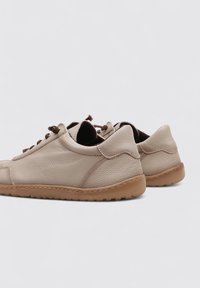 Light beige leather shoes with textured surfaces, round toe, and brown laces. Featuring a flexible rubber sole and stitched detailing.