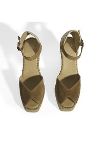 Bruine suede espadrille wedges met een kruislings ontwerp, enkelbandje en natuurlijke jute zool. Heeft een textuur op de hak en een zachte voering.